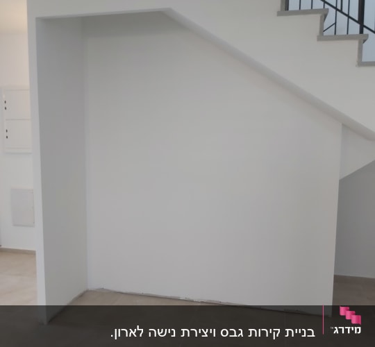 קיר גבס מתחת למדרגות עם רצפת אריחים